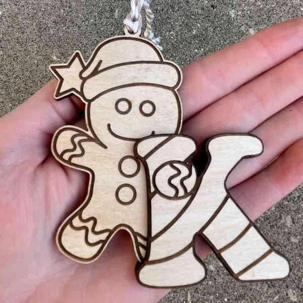 Laser-cut wooden gingerbread man ornament hugging a candy cane initial; customizable with a hand-painted letter or natural wood finish, crafted from birch veneer plywood. Custom Gingerbread Man Ornament with Candy Cane Initial